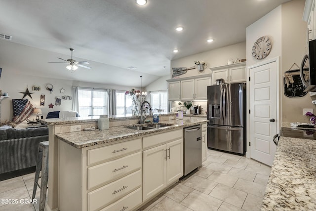 kitchen featuring light stone counters, appliances with stainless steel finishes, open floor plan, a sink, and an island with sink