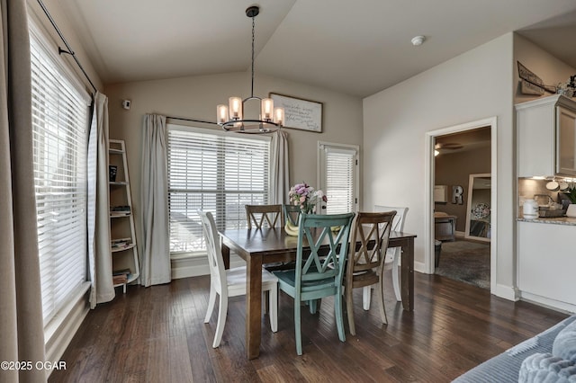 dining area with dark wood-type flooring, a notable chandelier, and vaulted ceiling