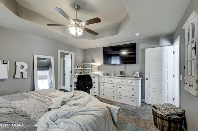 carpeted bedroom featuring visible vents, a tray ceiling, and ceiling fan