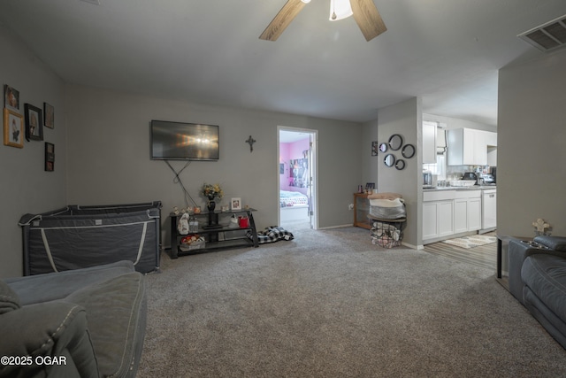 living room featuring light colored carpet, visible vents, and ceiling fan