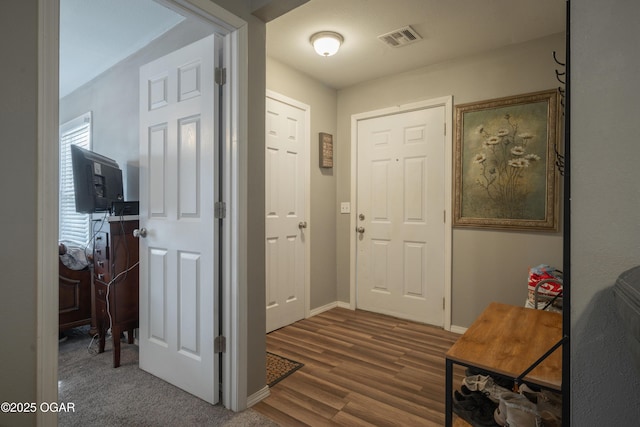 foyer entrance featuring visible vents, baseboards, and wood finished floors