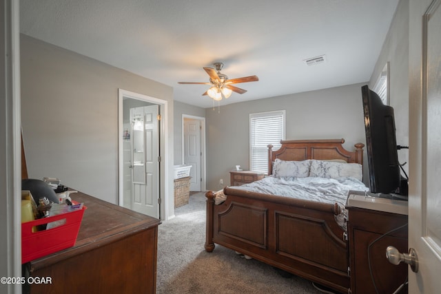 bedroom featuring ensuite bath, visible vents, dark carpet, and ceiling fan