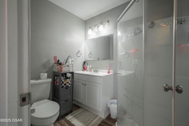 bathroom featuring a shower stall, vanity, toilet, and wood finished floors