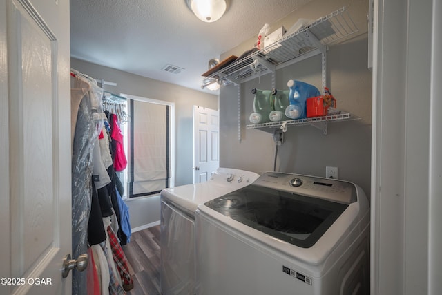 washroom with visible vents, laundry area, dark wood-style flooring, a textured ceiling, and washing machine and dryer