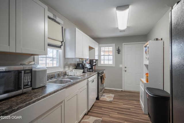 kitchen with visible vents, dark wood-style flooring, a sink, dishwasher, and stainless steel microwave