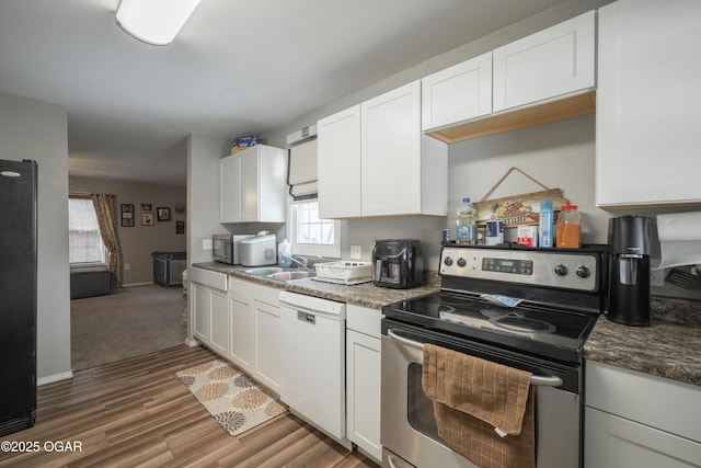 kitchen featuring wood finished floors, white cabinetry, stainless steel appliances, and a sink