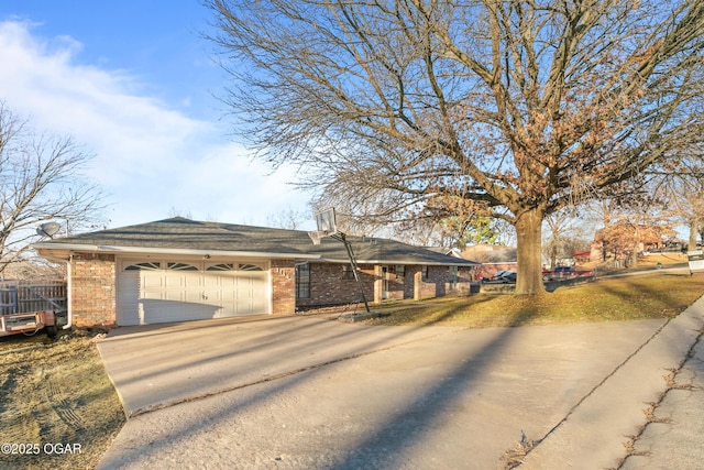 ranch-style home with concrete driveway, brick siding, fence, and an attached garage