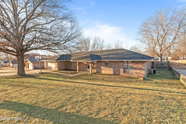 view of front of house featuring brick siding, fence, central AC, and a front lawn