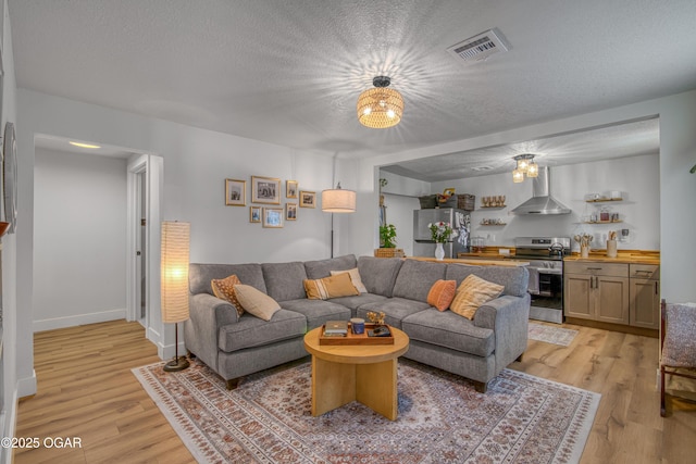 living area featuring light wood-type flooring, visible vents, and a textured ceiling