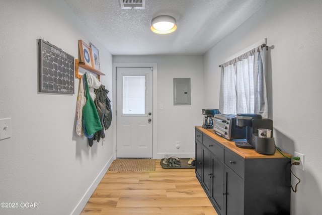 entryway with electric panel, baseboards, visible vents, light wood-style flooring, and a textured ceiling