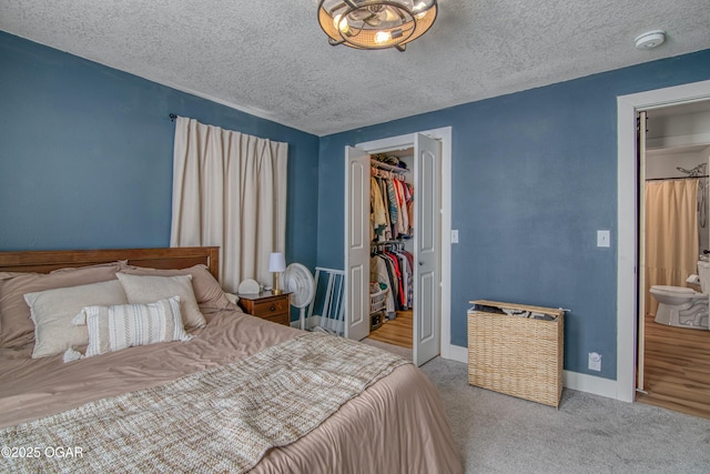 bedroom with baseboards, carpet, a spacious closet, a textured ceiling, and a closet