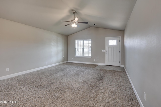 interior space with vaulted ceiling, carpet floors, ceiling fan, and baseboards