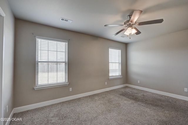 carpeted spare room featuring ceiling fan, visible vents, and baseboards