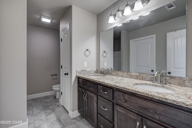 full bath with toilet, double vanity, baseboards, and a sink