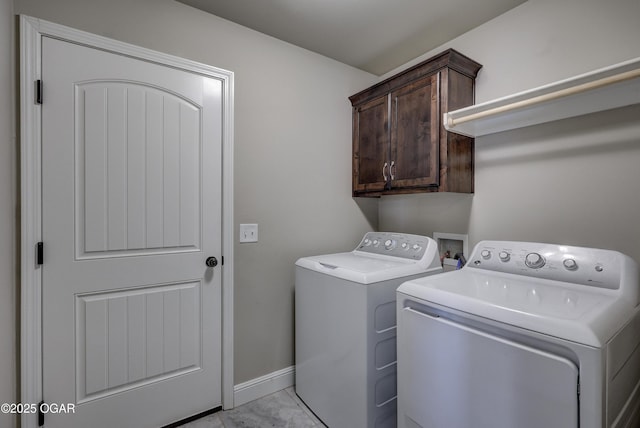 laundry area featuring baseboards, cabinet space, and washing machine and clothes dryer