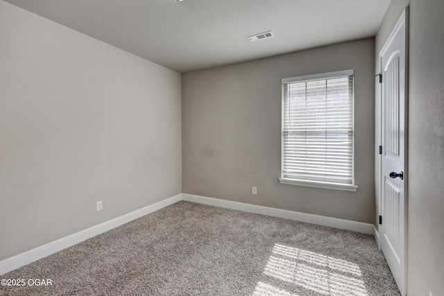 spare room featuring a wealth of natural light, carpet, visible vents, and baseboards