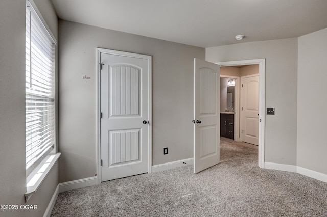 unfurnished bedroom featuring multiple windows, carpet flooring, and baseboards