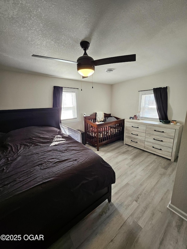 bedroom featuring light wood-type flooring, a textured ceiling, and a ceiling fan