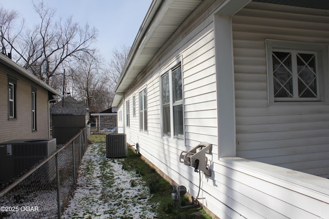 view of side of property with central AC unit and fence