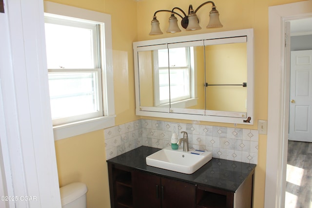 bathroom featuring toilet, backsplash, and vanity