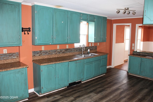 kitchen featuring crown molding, dark countertops, a sink, and dark wood-style floors