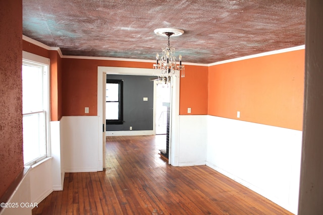 empty room featuring dark wood-style floors, a chandelier, and crown molding