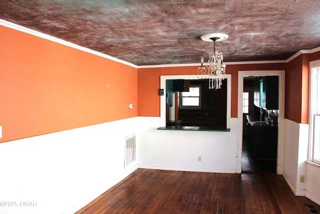 unfurnished dining area featuring dark wood-style floors, visible vents, ornamental molding, and an inviting chandelier