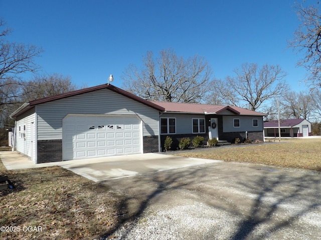 ranch-style house with a garage, concrete driveway, and metal roof