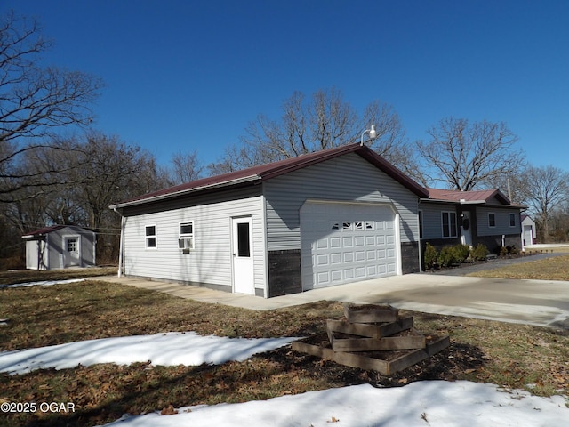 view of side of home featuring an outbuilding, an attached garage, cooling unit, driveway, and a shed