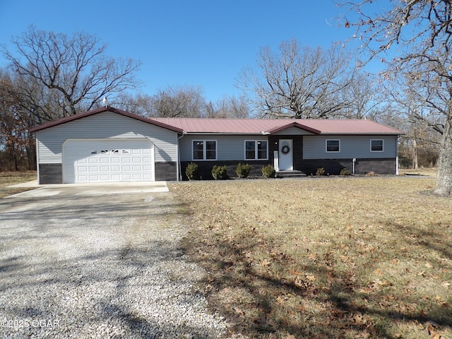 single story home featuring metal roof, an attached garage, driveway, and a front yard