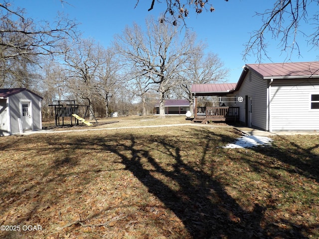 view of yard with a shed, an outdoor structure, a playground, and a wooden deck