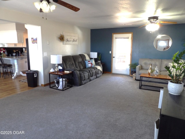 carpeted living room with baseboards and a ceiling fan