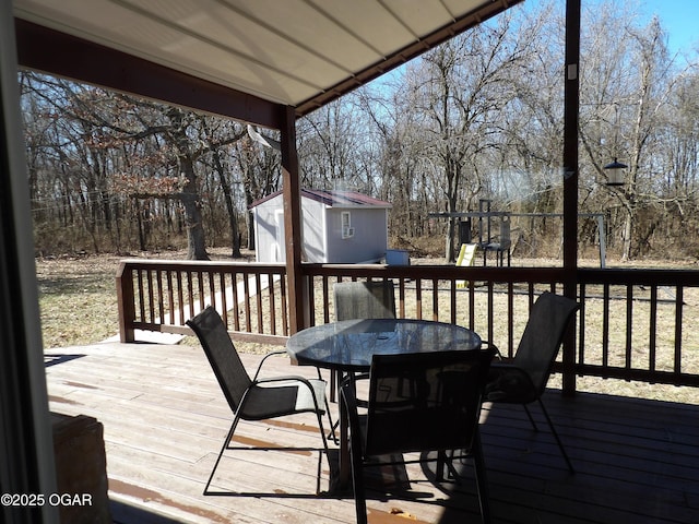 deck featuring a storage unit, outdoor dining area, and an outdoor structure