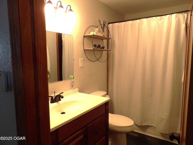 full bath with a textured wall, vanity, and toilet