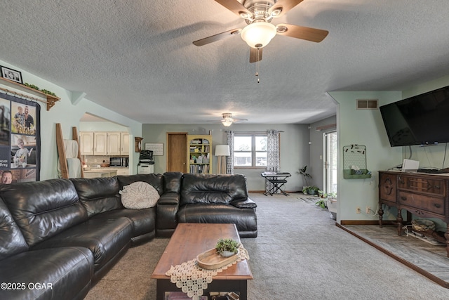 living room featuring light colored carpet, visible vents, ceiling fan, a textured ceiling, and baseboards