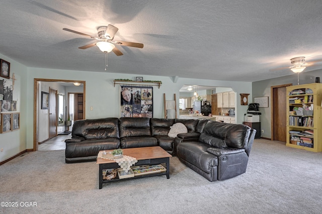 living room with a textured ceiling, ceiling fan, and light colored carpet