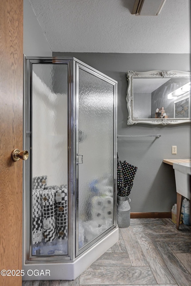 bathroom with baseboards, a shower stall, and a textured ceiling