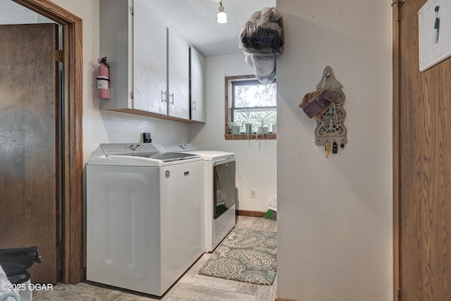 laundry area featuring washing machine and dryer, cabinet space, and baseboards