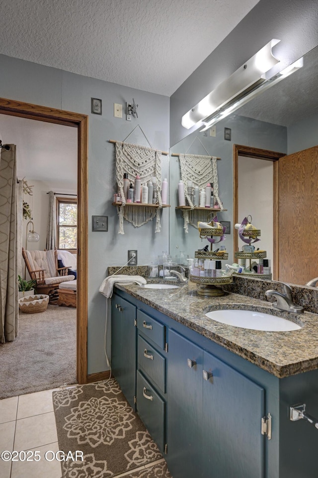 full bathroom with tile patterned flooring, a sink, a textured ceiling, and double vanity