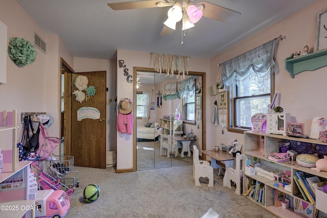 interior space with carpet floors, visible vents, a textured ceiling, and a ceiling fan