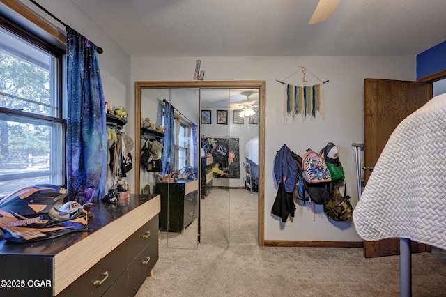 bedroom with ceiling fan, a textured ceiling, light carpet, baseboards, and a closet