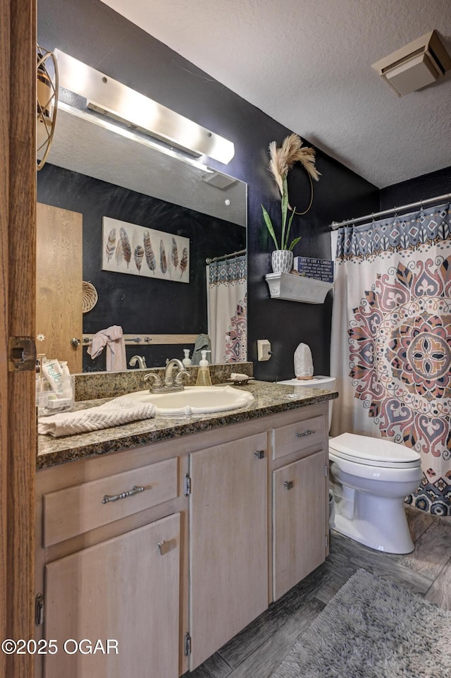 bathroom with visible vents, a textured ceiling, toilet, and vanity