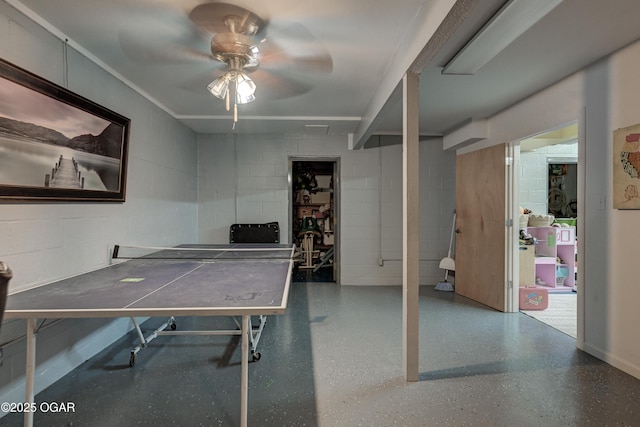 rec room with speckled floor, concrete block wall, and a ceiling fan