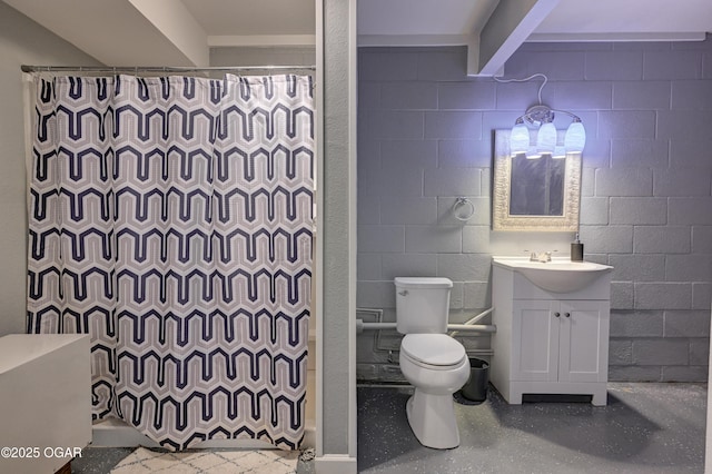 full bath featuring toilet, curtained shower, vanity, and concrete block wall