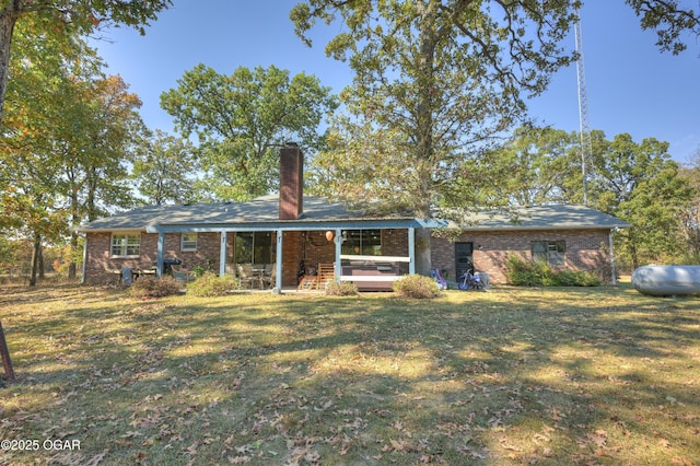 rear view of property featuring brick siding, a lawn, and a chimney