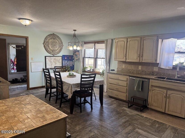 kitchen with a textured ceiling, a sink, hanging light fixtures, stainless steel dishwasher, and tasteful backsplash