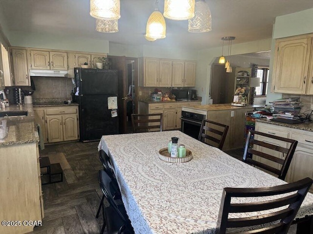 kitchen featuring black appliances, under cabinet range hood, backsplash, and a sink