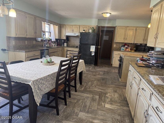 kitchen featuring black appliances, under cabinet range hood, backsplash, and a sink