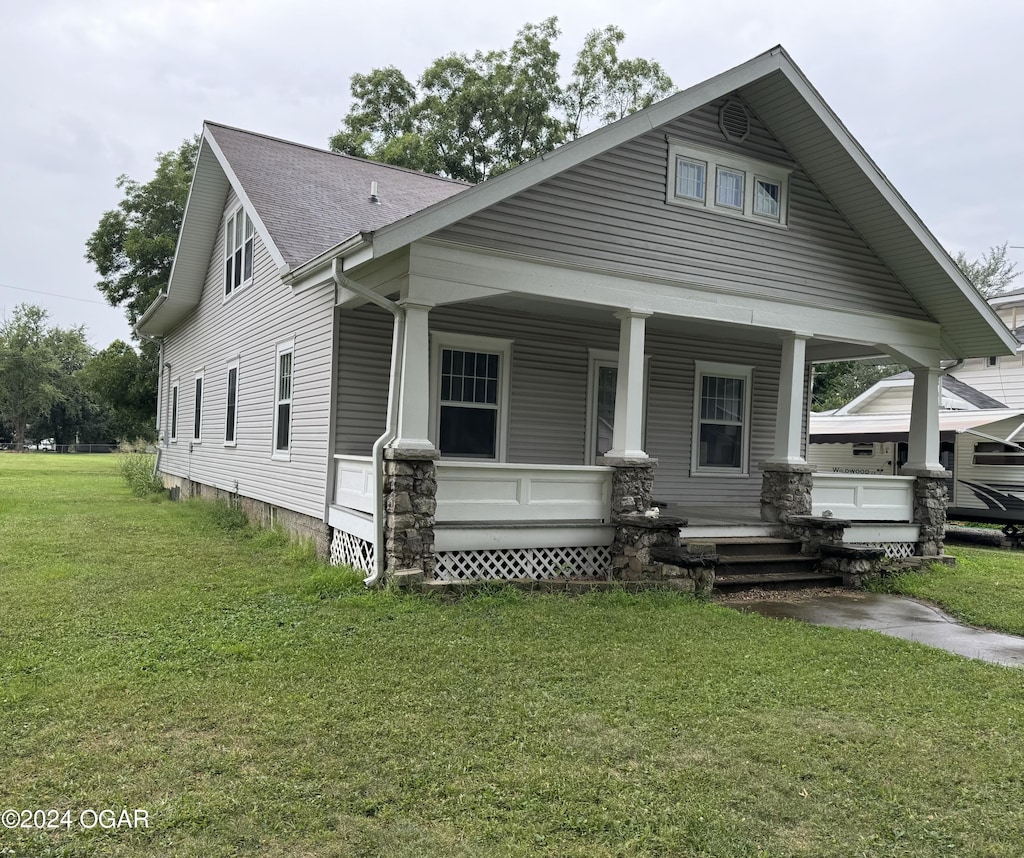 707 Grand St, Lamar, MO 64759 - view of front of house featuring a porch, roof with shingles, and a front lawn