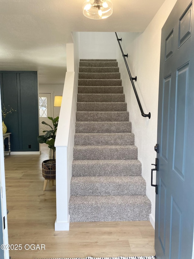 staircase with baseboards and wood finished floors